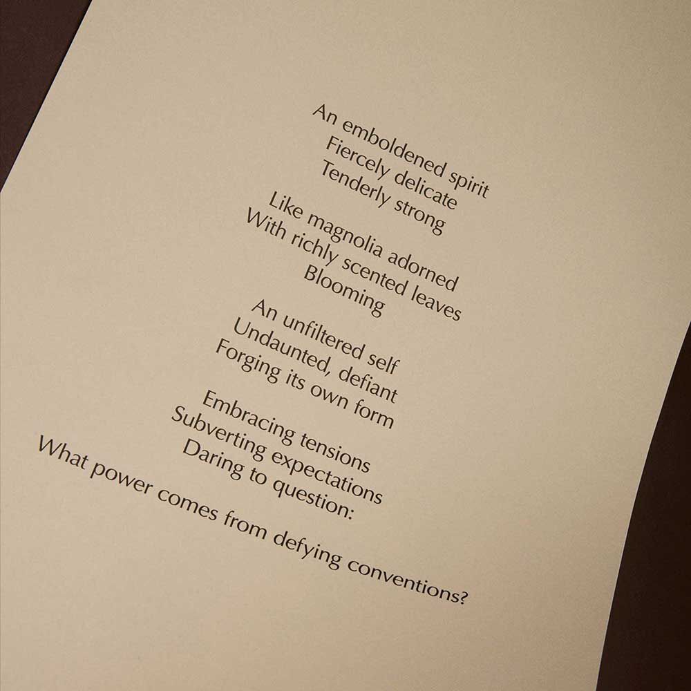 Curved cream page with printed verse against a dark brown background.