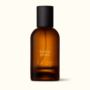 Amber glass Aesop Evoking Eidesis Eau de Parfum bottle with black cap on a white background.