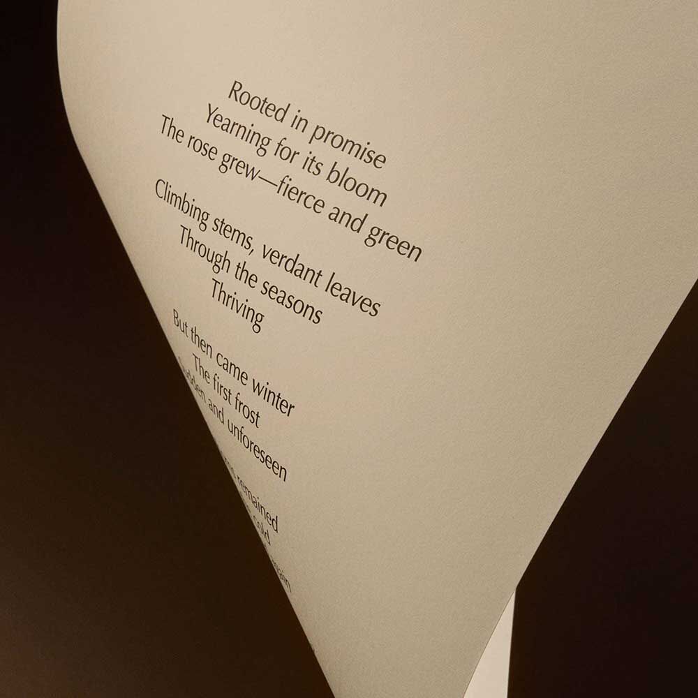 Curved cream page with printed verse against a dark brown background.