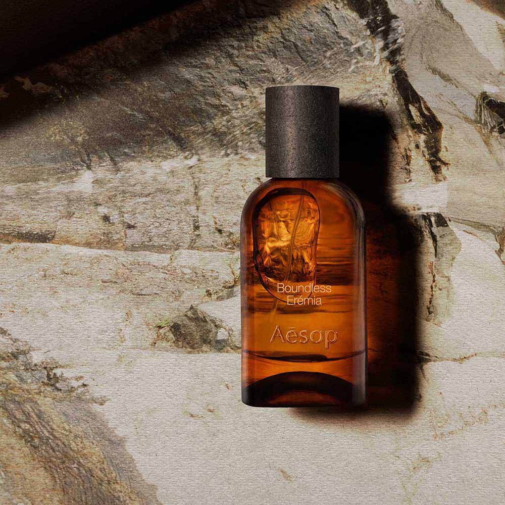 Aesop Boundless Eremia bottle on a pale veined stone surface.