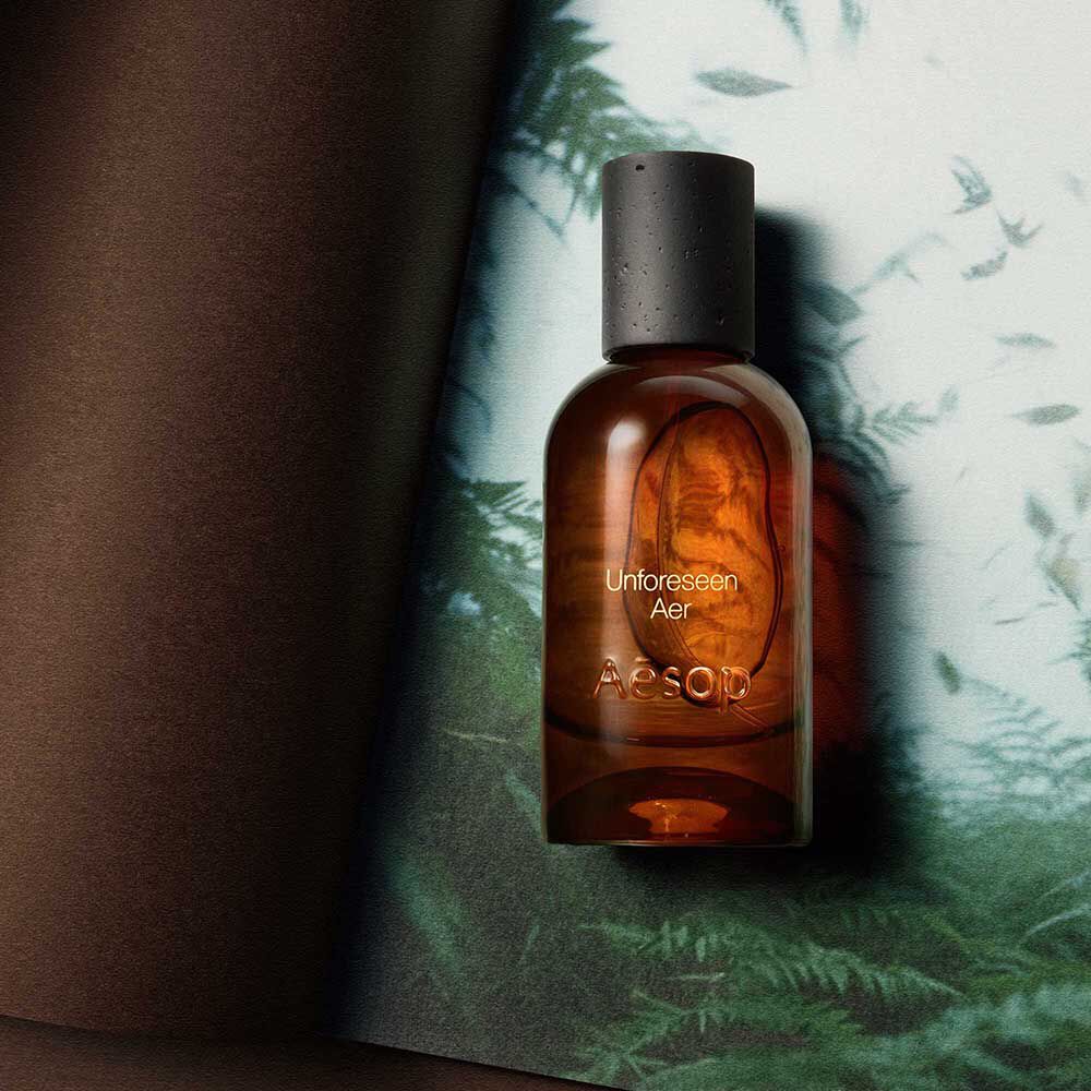 Aesop Unforeseen Aer bottle on a fern-patterned pale surface.