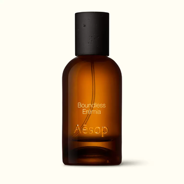Amber glass Aesop Boundless Eremia Eau de Parfum bottle with black cap on a white background.